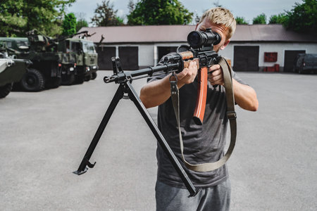 Close-up of a man holding an assault rifle with a sniper scopeの写真素材