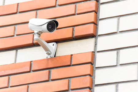 A security camera is mounted on a brick wall, ensuring surveillance and safety. The sturdy setup is...