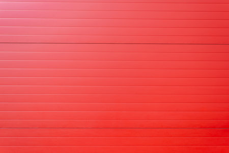 A bright red garage door with a slatted design, perfect for modern homes. The bold color adds a...