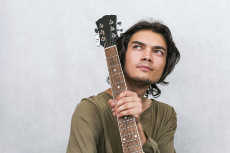 A thoughtful person with an acoustic guitar looks upwards, conveying inspiration, creative contemplation, or the joy of music, perfect for artistic and hobby themes.の写真素材