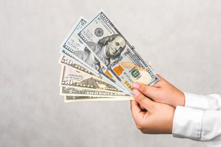 A child's hands proudly display fanned US dollar banknotes, symbolizing early financial education,...