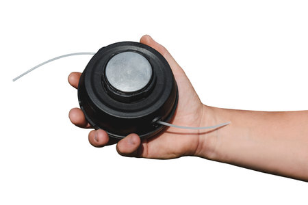 Close-up of hands holding a trimmer head with line. Isolated concept of gardening equipment for lawn...