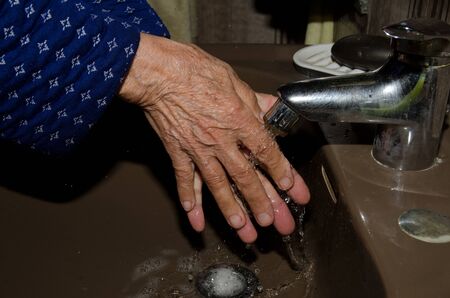 Older woman washing her hands to prevent coronavirusの写真素材