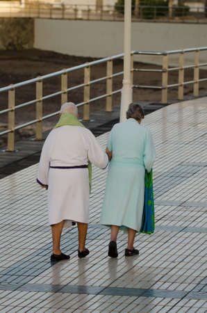 Older couple going for a swim in the sea. Playa de Arinaga. Aguimes. Gran Canaria. Canary Islands. Spain.の写真素材