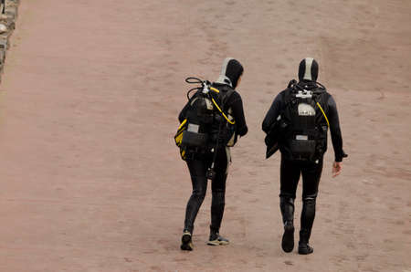 Couple of divers getting out of the water. Los Cristianos. Arona. Tenerife. Canary Islands. Spain.