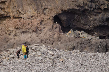 Three people talking and one doing yoga in a cave on the right. Tapahuga Ravine. San Sebastian de La Gomera. La Gomera. Canary Islands. Spain.の写真素材