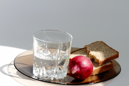 a glass of vodka and onion, bread on a dark plate  の写真素材