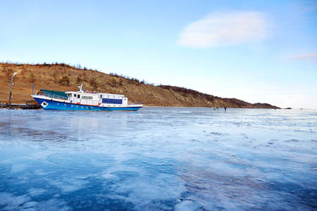 Lake Baikal in December. View of the frozen Kurkut Bay in the rays of the setting sun. Larch on the shore is reflected in the frozen surface of the lake.の写真素材