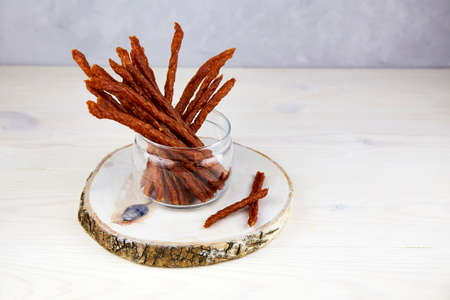 Jerky meat. Homemade dried meat sausages in a glass jar on wooden background. High quality photoの写真素材
