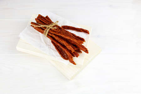 Jerky meat. Homemade dried meat sausages on wooden background. High quality photoの写真素材