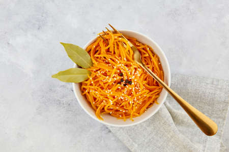 Spicy pickled carrots in a bowl on a gray background, spicy Korean appetizer. Vegan healthy food. Close-up.の写真素材