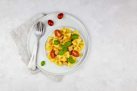 Pasta farfalle bolognese with tomato sauce, cherry tomatoes and basil on a gray background.の写真素材