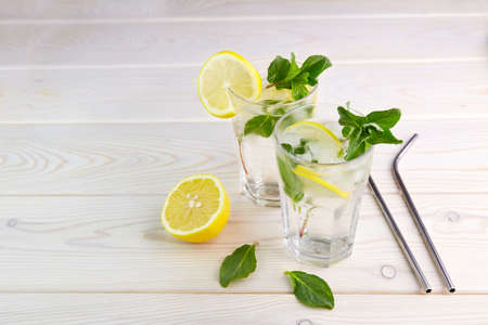 Two glasses with lemonade or mojito on wooden background. Fresh cold refreshing summer cocktail with lemon, mint and ice.の写真素材