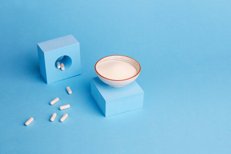 Collagen protein powder and capsules on a blue background. A food supplement for the skin and...