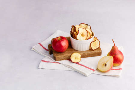 Homemade dried sliced apple and pear in a bowl on a light gray background. Fruit chips. Vegan dessert sugar free.の写真素材