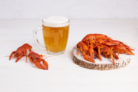 A mug of light beer with boiled crayfish on a wooden boardの写真素材