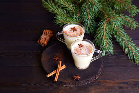 Traditional Christmas drink eggnog with eggs, milk, grated nutmeg and cinnamon on a dark wooden background. High quality photoの写真素材