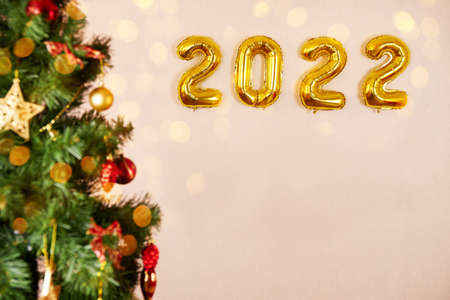 Christmas and New Year background. Christmas tree, golden helium balloons number 2022 New Year, bokeh, sparkling lights. Greeting card, banner, poster. High quality photoの写真素材