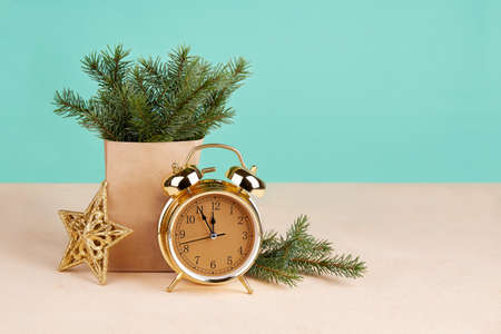 Happy New Year or Merry Christmas Greeting card. Spruce branches in a kraft bag, a golden alarm clock and a Christmas tree toy. Copy space.の写真素材