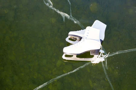 White women's skates for figure skating on the ice of the lake. Natural background, transparent ice of Lake Baikal.の写真素材
