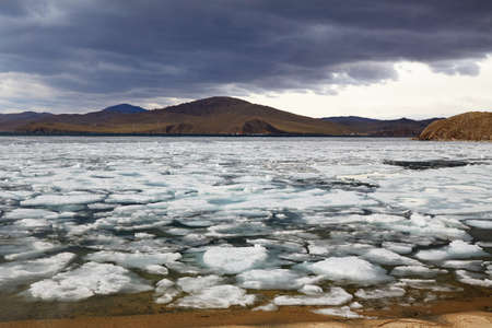Spring landscape of Lake Baikal on a cloudy day. Ice drift, ice floes in the lake