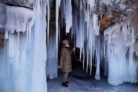 A woman explores huge icicles in the ice cave of Oltrek Island. Winter trip on the frozen Lake...