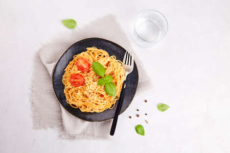 Italian pasta spaghetti with tomatoes, tomato sauce, basil on a dark plate on a gray background.の写真素材