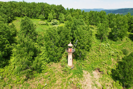 An old lighthouse on a mountain covered with forest on a summer day. aerial view.の写真素材