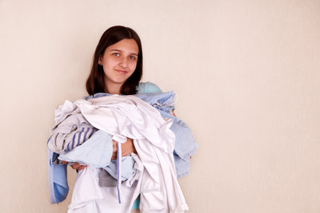 A young smiling girl with a bunch of clothes.の写真素材