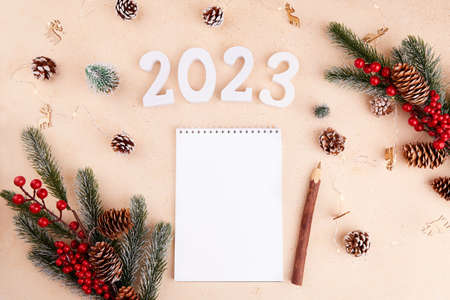 A notebook, a blank sheet of paper for a to-do list, plans, and wishes for the new year 2023. Christmas greeting card. top viewの写真素材