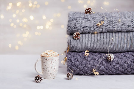 A stack of knitted sweaters or scarves, a cup of cocoa with marshmallowsの写真素材