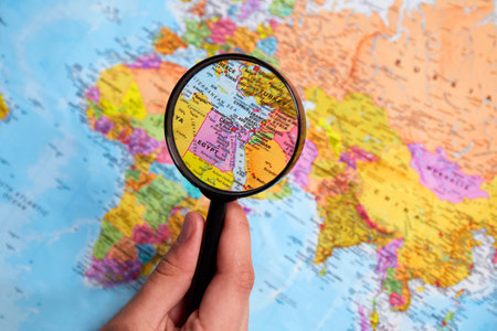 The hand holds a magnifying glass over the world map. concept of travel.の写真素材