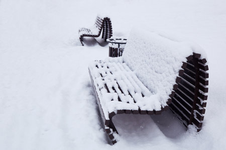 Wooden benches in the snow in the city park. Heavy snowfall, snowdrifts.の写真素材