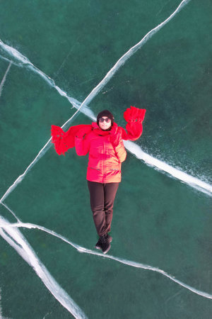 A female tourist on the background of transparent ice with cracks