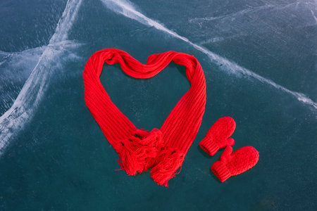 Red heart-shaped scarf and mittens on ice.