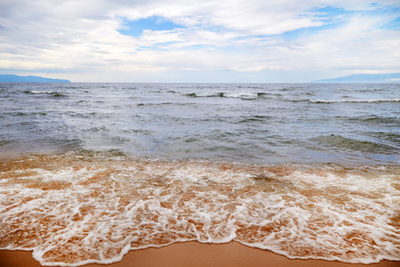 summer seascape. Waves on a sandy beach on a cloudy day.の写真素材