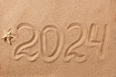 Happy New Year 2024 greeting card. The numbers 2024 on the sand on the beach, a starfish. Natural...