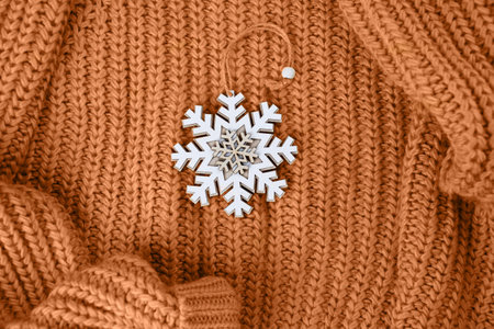 Wooden snowflake toy for a Christmas tree on a knitted wool sweater. Festive background. Peach Fuzz Color of Year 2024.の写真素材