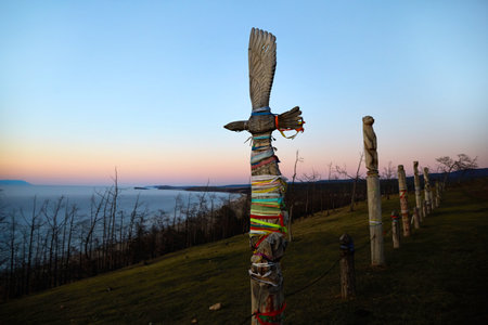 Sunset over Lake Baikal in spring. Colored ribbons on a wooden post with the shape of a bird. A place for making wishes on the island of Olkhon.の写真素材