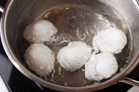 Chicken white eggs in boiling water in a metal saucepan. Boiled eggs.