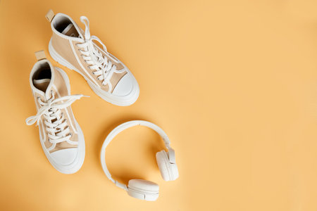 Converse sneakers and white headphones on an isolated orange background. Running and walking shoes. Top viewの写真素材