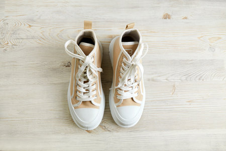A pair of beige sneakers on wooden background. Running shoes Top view.の写真素材