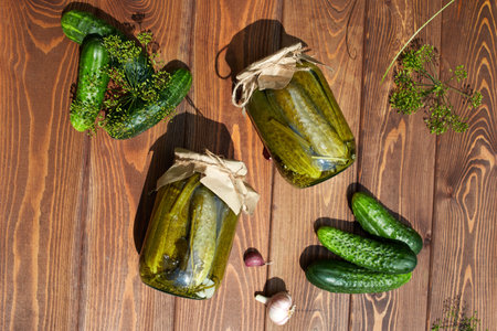 Pickled cucumbers in jars, fresh cucumbers on a wooden table . Home canning.の写真素材