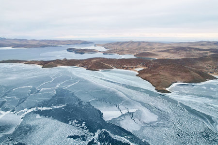 Frozen Lake Baikal from the air. Cloudy stormy sky, clear ice in the cracks. Winter landscape.の写真素材