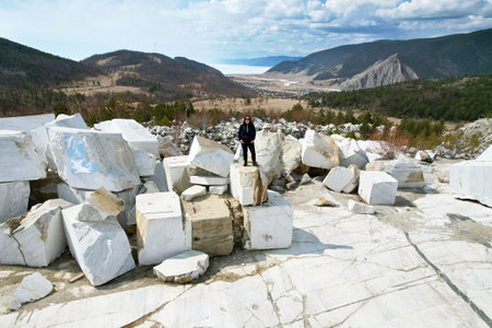 A woman stands on huge blocks of white marble. An abandoned marble quarry. A popular tourist spot near the village of Buguldeika. Aerial viewの写真素材