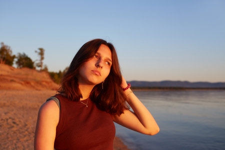 A girl enjoys the sunset on a sandy beach. Summer travel, sea holidays.の写真素材