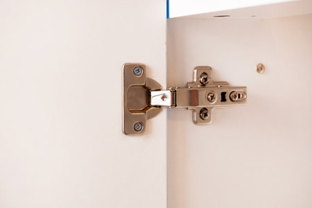 A metal cabinet hinged attached to a white cabinet door.の写真素材