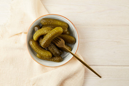 Marinated gherkins in a bowl on a light wooden background. Homemade pickles. Close-upの写真素材