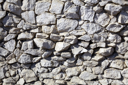 Natural stone wall showcases varied textures and colors in an outdoor setting during daylight hours