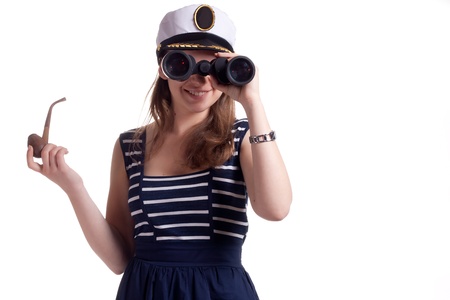 A girl in a sailor cap holding a pipe for smoking and looking through binoculars on a white backgroundの写真素材